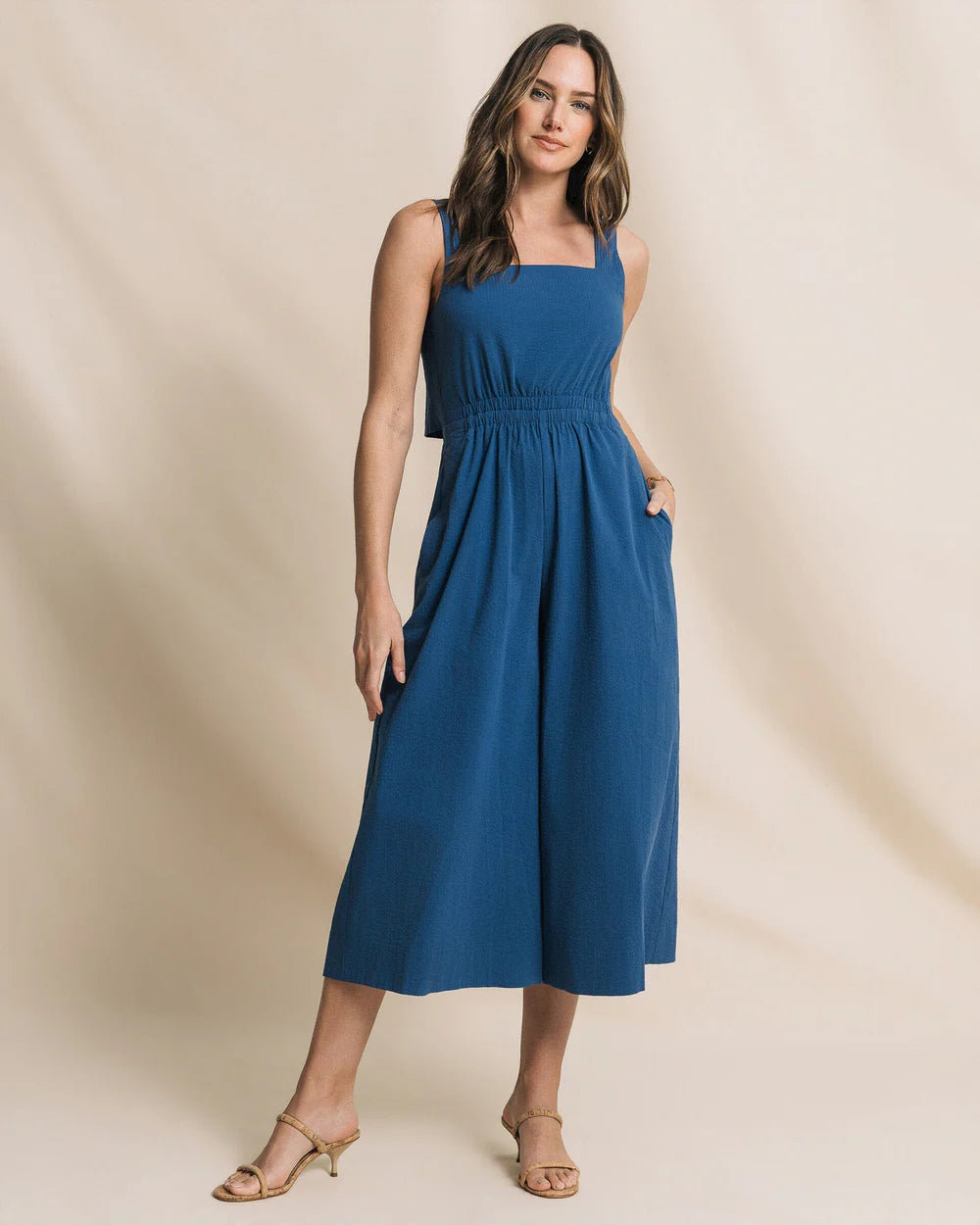 Woman wearing a blue dress against a beige background