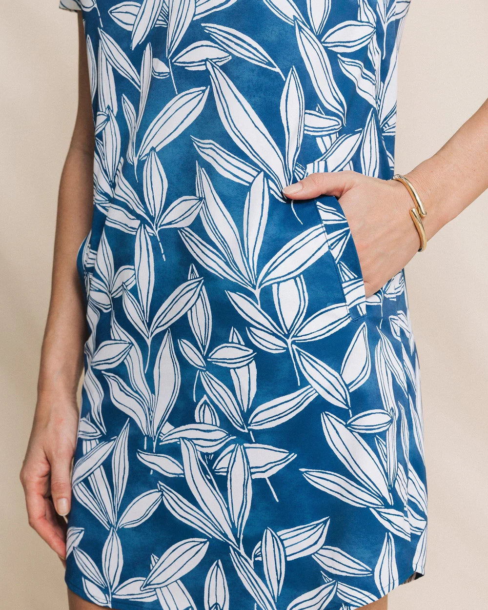 Blue dress with white leaf pattern worn by a person on a beige background