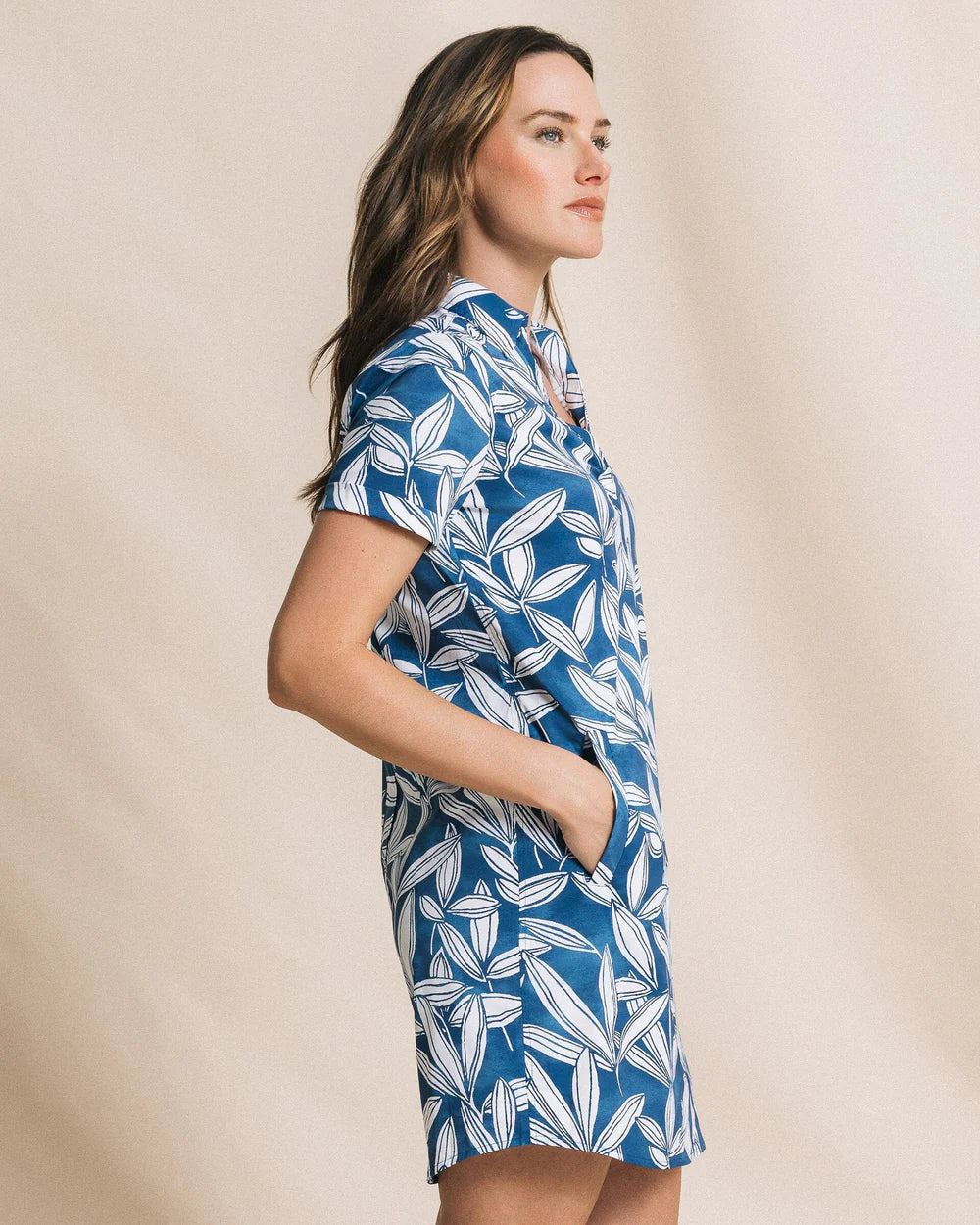 Woman wearing a blue and white patterned dress against a beige background