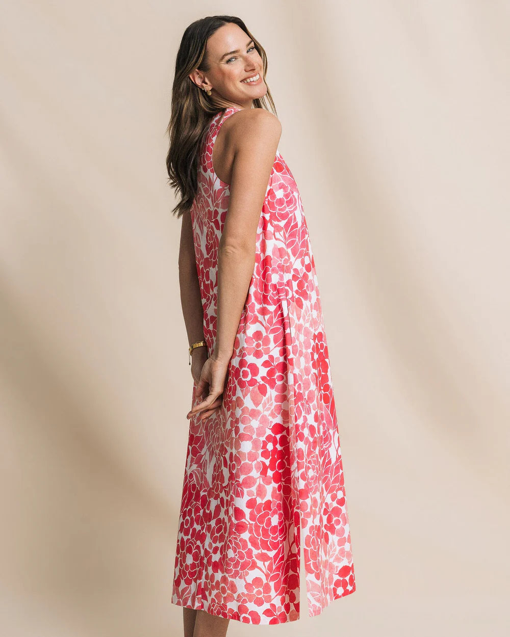 Woman wearing a red floral dress against a beige background