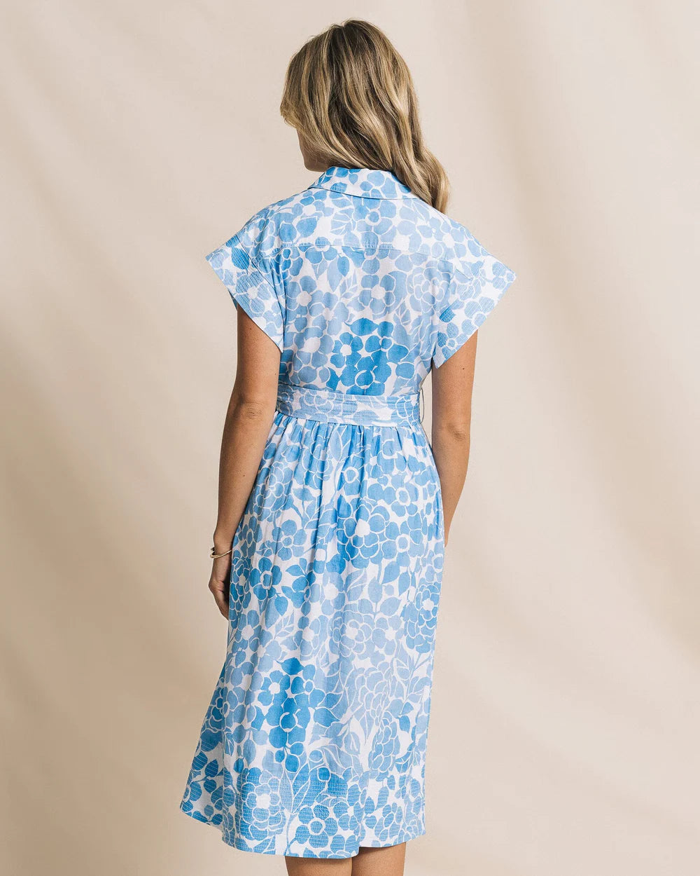 Woman wearing a blue floral dress against a beige background