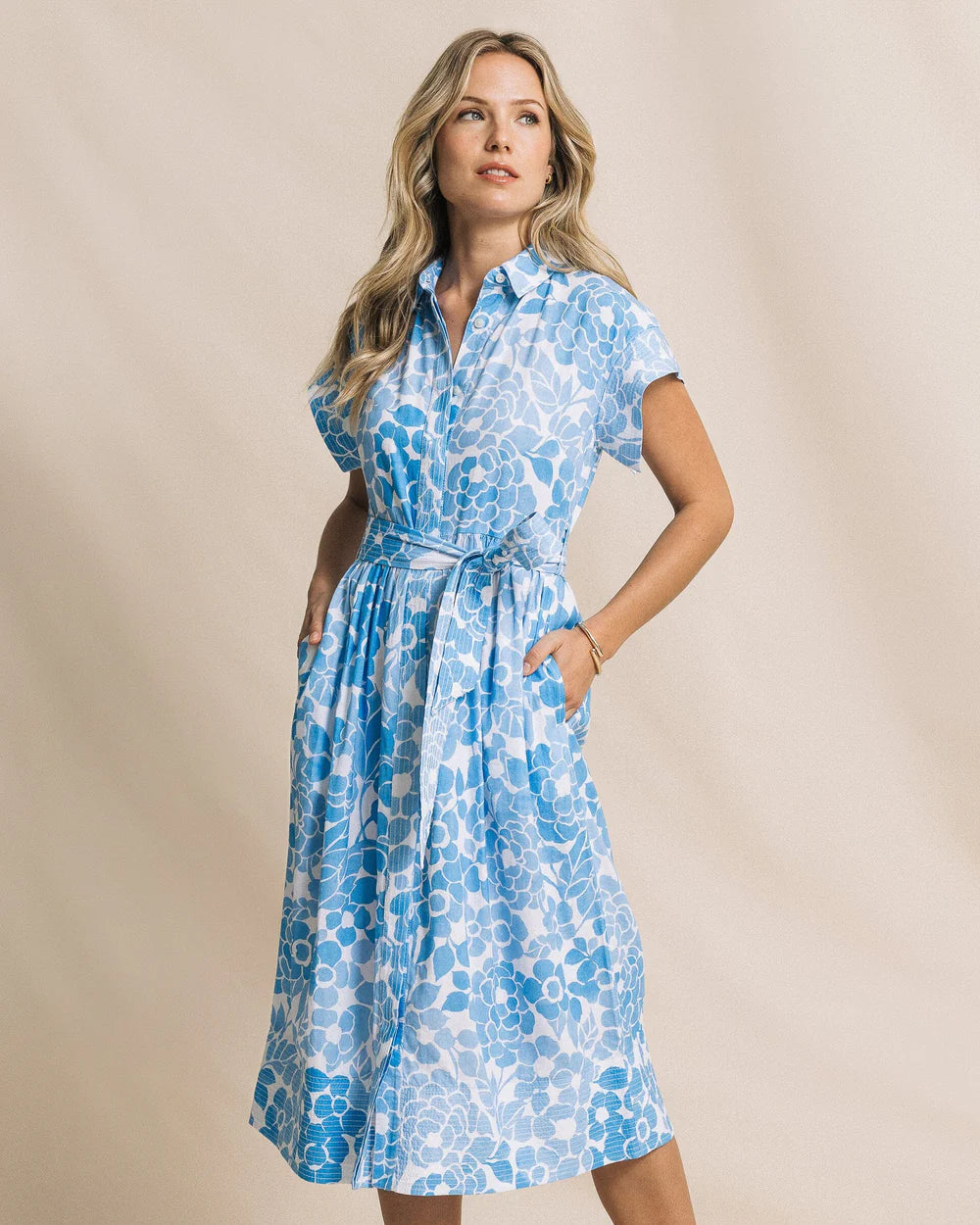 Woman wearing a blue floral dress against a beige background