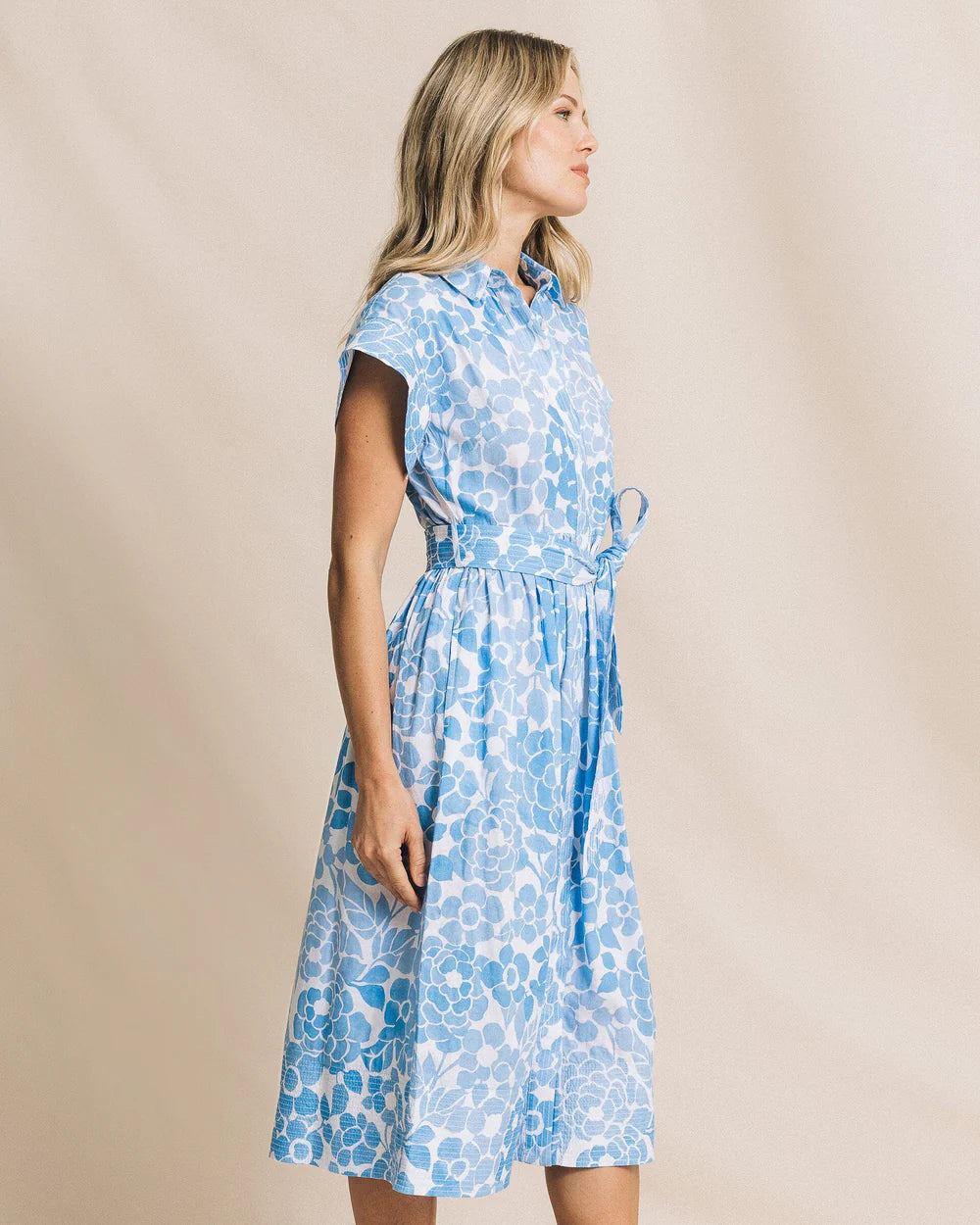 Woman wearing a blue floral dress against a beige background
