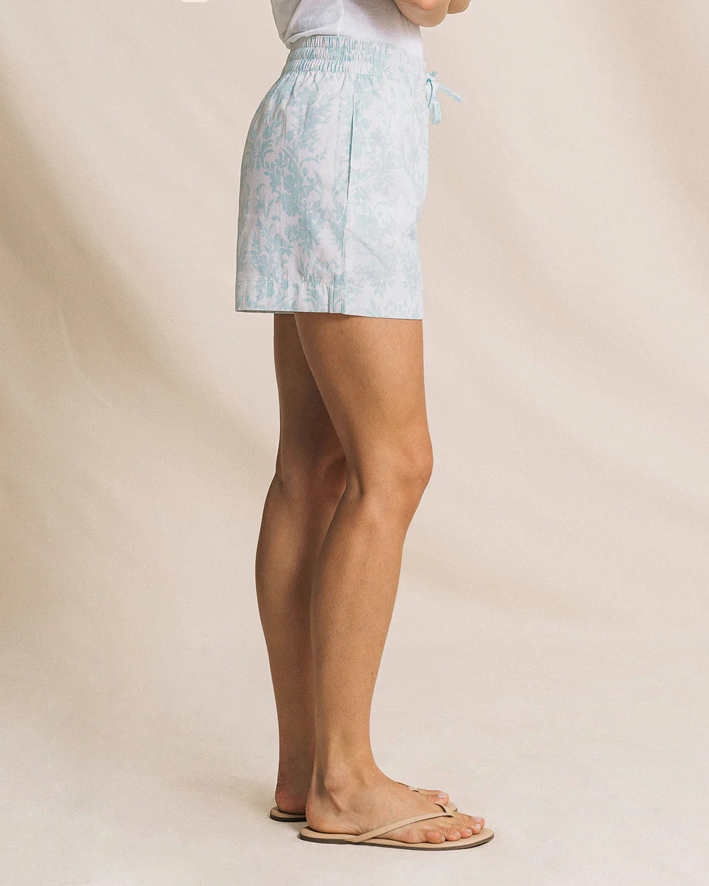 Person wearing a light blue patterned skirt on a plain background